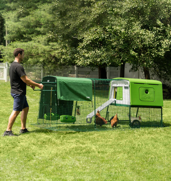 Homme déplaçant le Eglu Cube poulailler portable avec roues et poignées