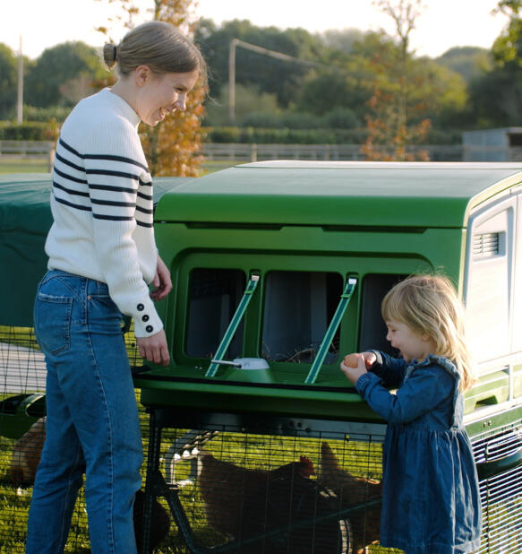 Mère et fille ramassant les oeufs dans le nichoir vert du poulailler Eglu pro.