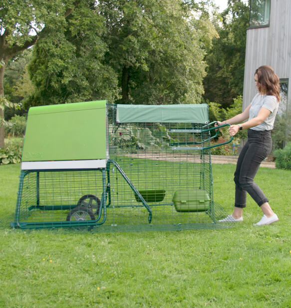 Femme déplaçant le poulailler portable Eglu Go dans son jardin